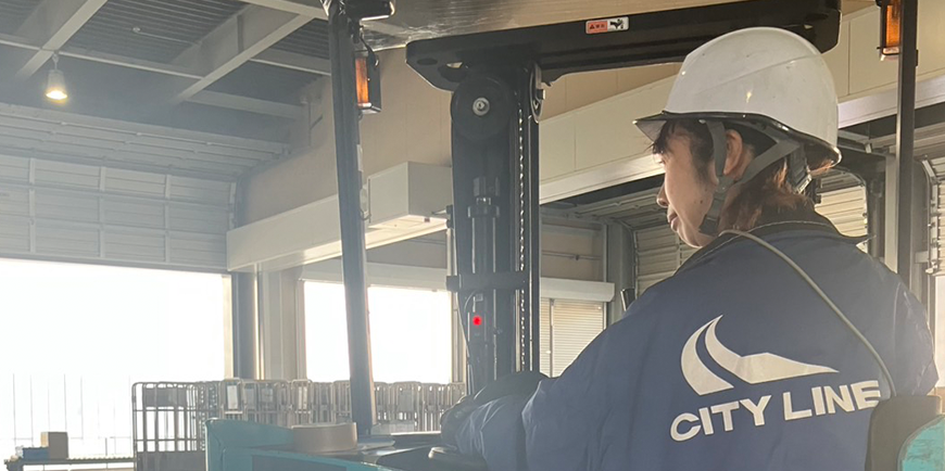 倉庫前に並ぶ複数のトラックが出荷準備をしている様子