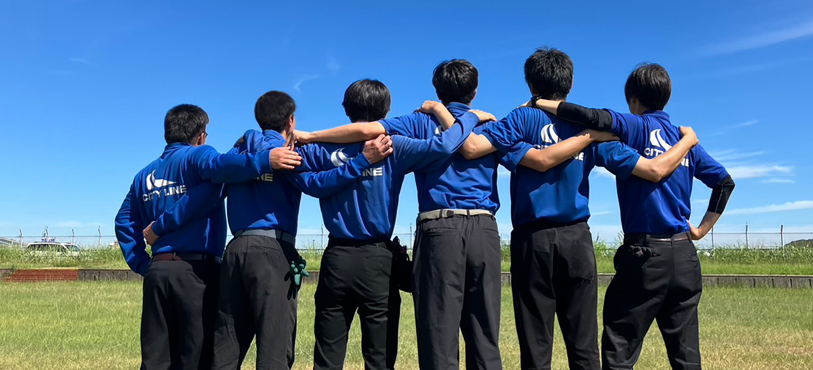 屋外で肩を組むスタッフの写真